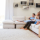 Family of our sitting on white couch watching TV in family room