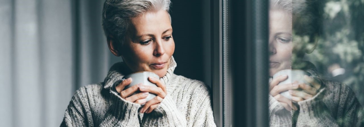 Woman in cozy sweater looking at window