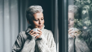 Woman in cozy sweater looking at window