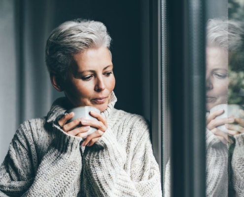 Woman in cozy sweater looking at window