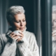 Woman in cozy sweater looking at window