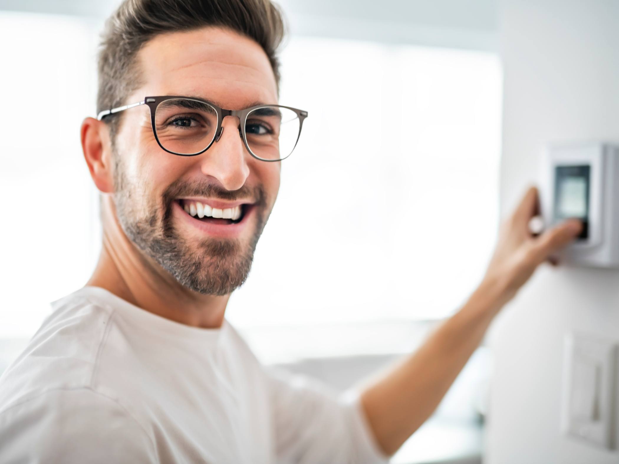 Cheerful man set the thermostat at house
