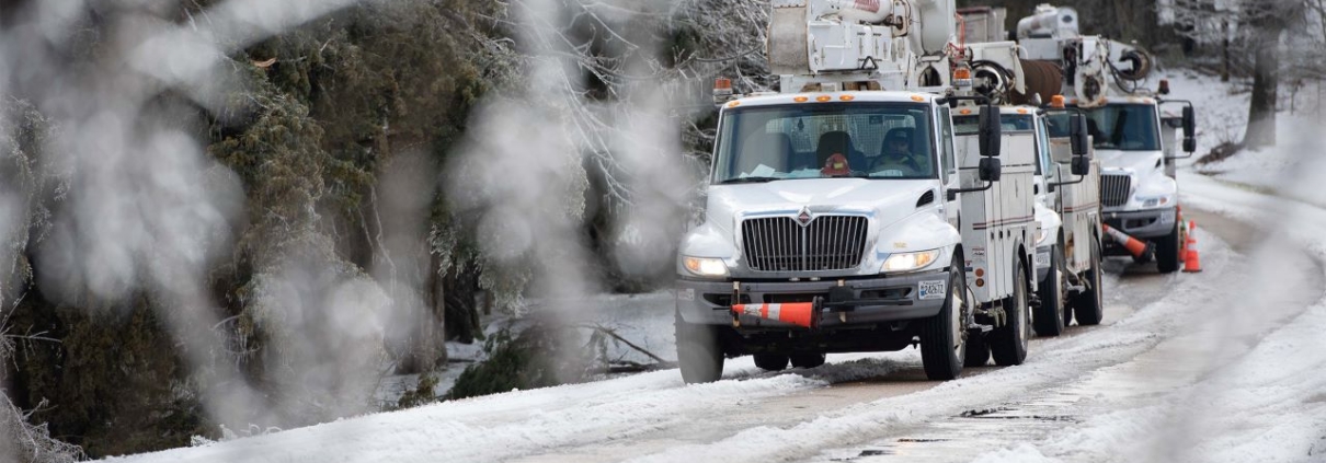 Utility bucket trucks lined up on iced over road in Vicksburg, Mississippi