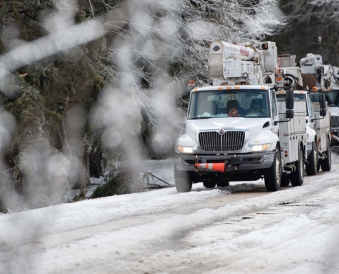 Utility bucket trucks lined up on iced over road in Vicksburg, Mississippi